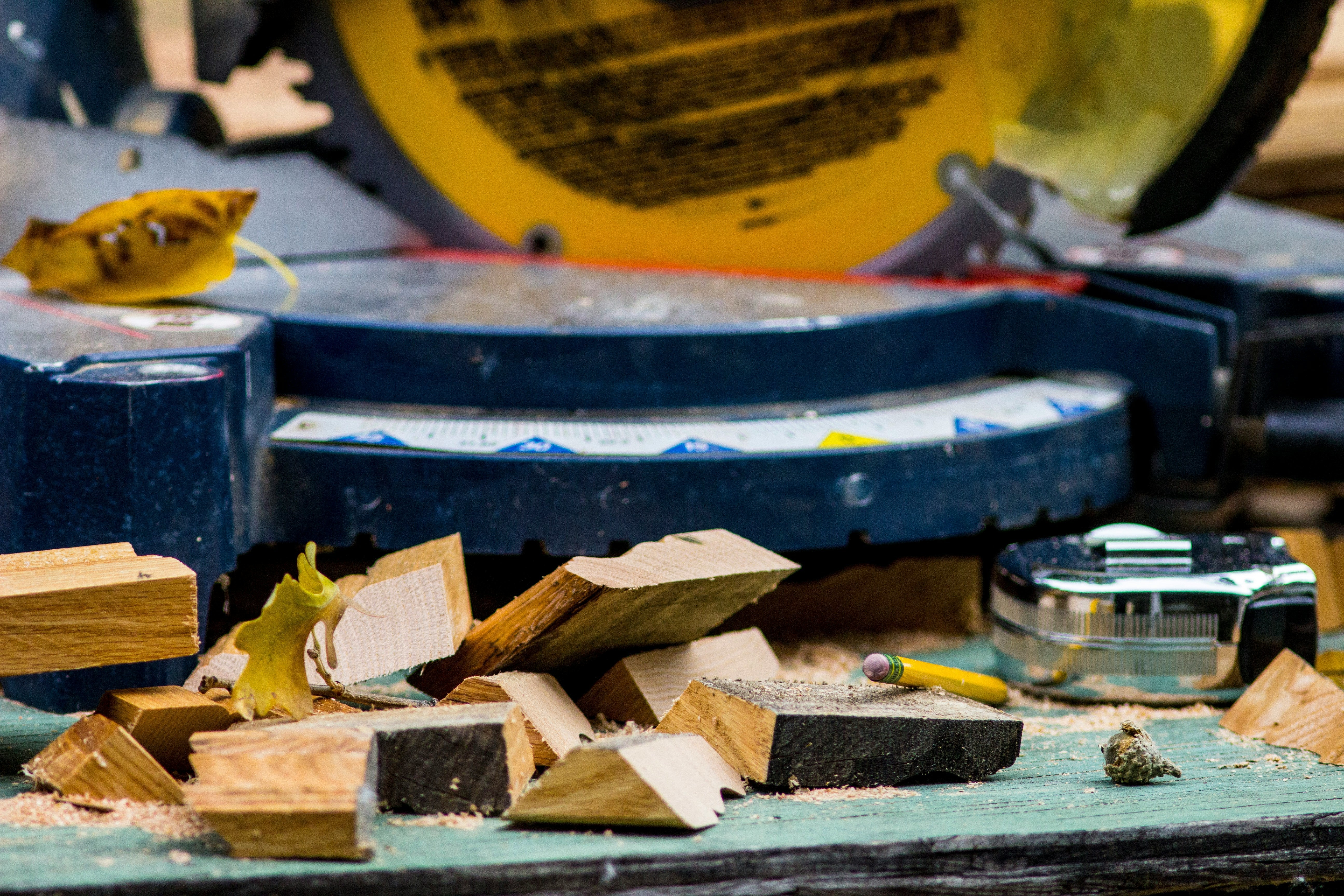 pieces of wood laying in front of a saw with a pencil and tape measure.